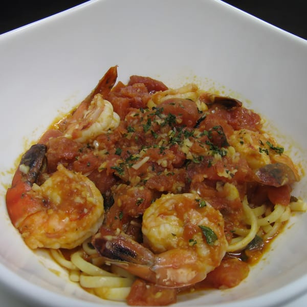 Cajun shrimp and pasta dish with a rich tomato sauce, garlic, and herbs in a white bowl.
