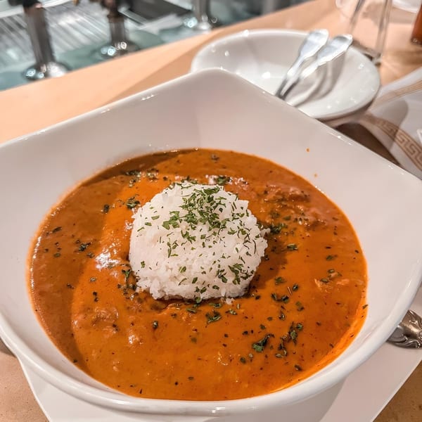 A white bowl of Cajun gumbo with a scoop of white rice topped with parsley.